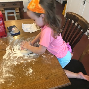 girl kneading dough on kitchen table
