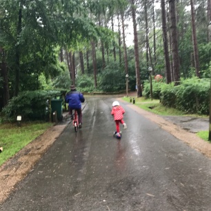 child cycling next to grandad in the forest